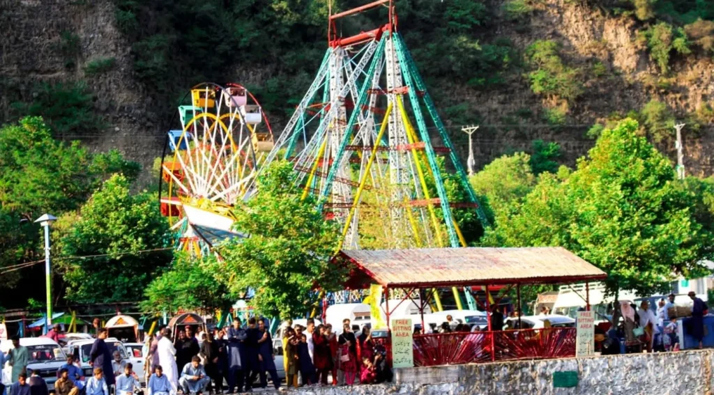 Families enjoying swings, slides, and trampolines at Harnoi Water Park Abbottabad on a busy weekend